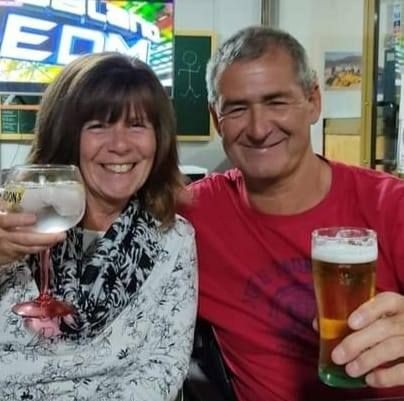 A smiling woman and man sitting together, each holding a glass of drink in their hands.