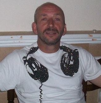 Man with headphones around his neck, wearing a white shirt, and sitting indoors.