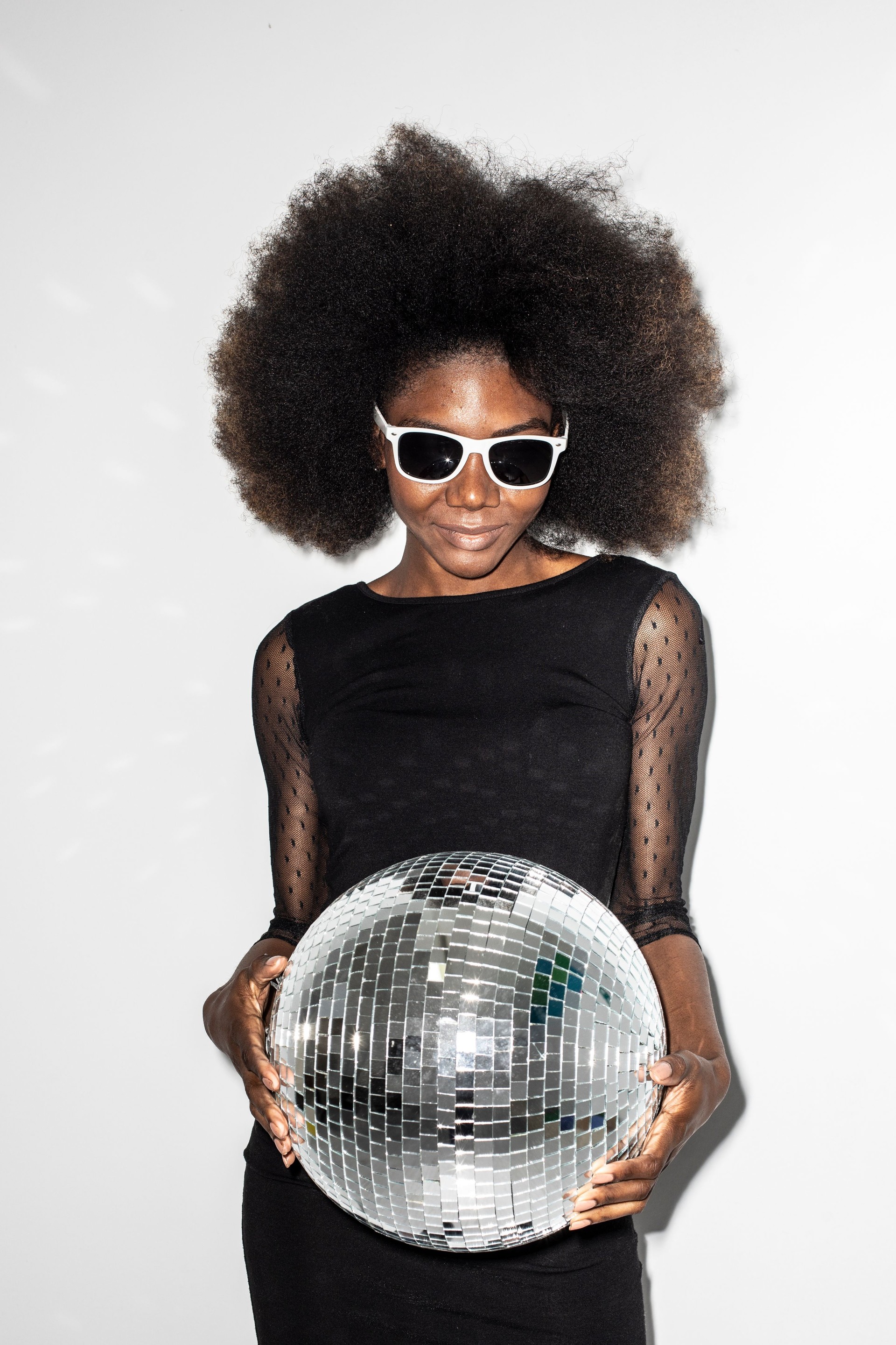 Happy woman in black dress holding disco ball
